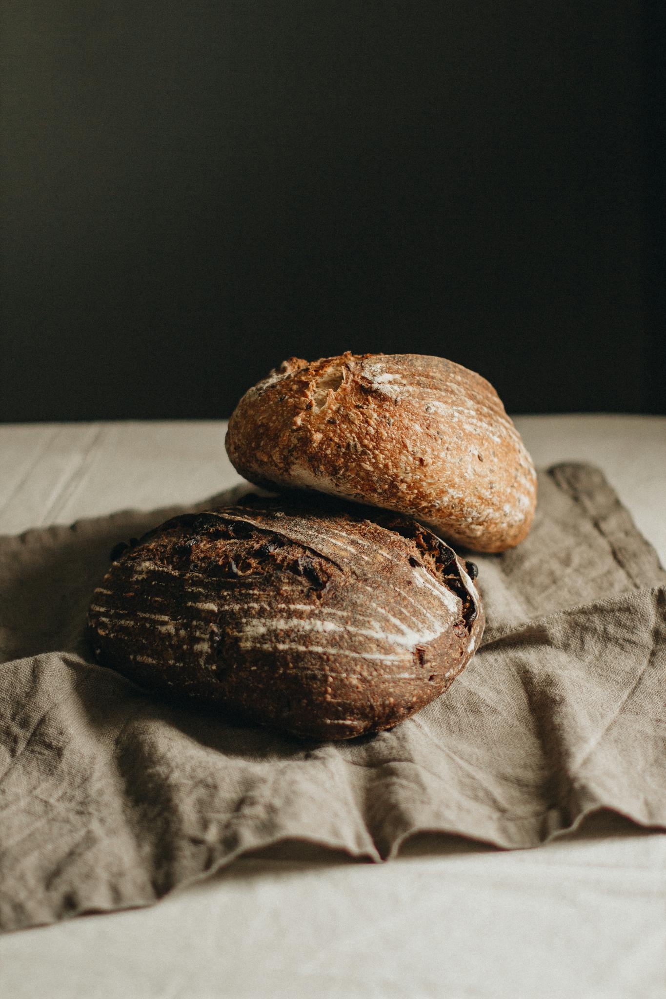 A vertical shot of two artisan bread loaves on a linen cloth, highlighting their rustic texture and freshness.